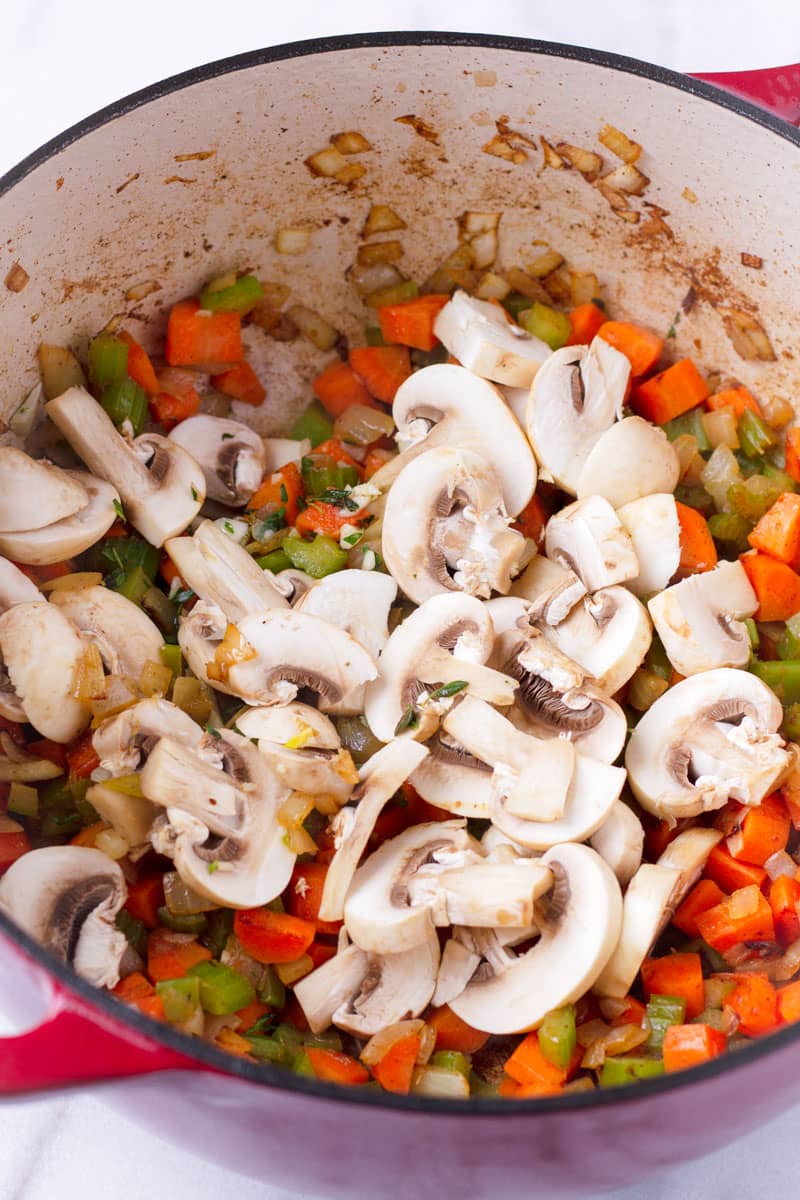large Dutch oven with sauteed carrots, celery, and sliced mushrooms
