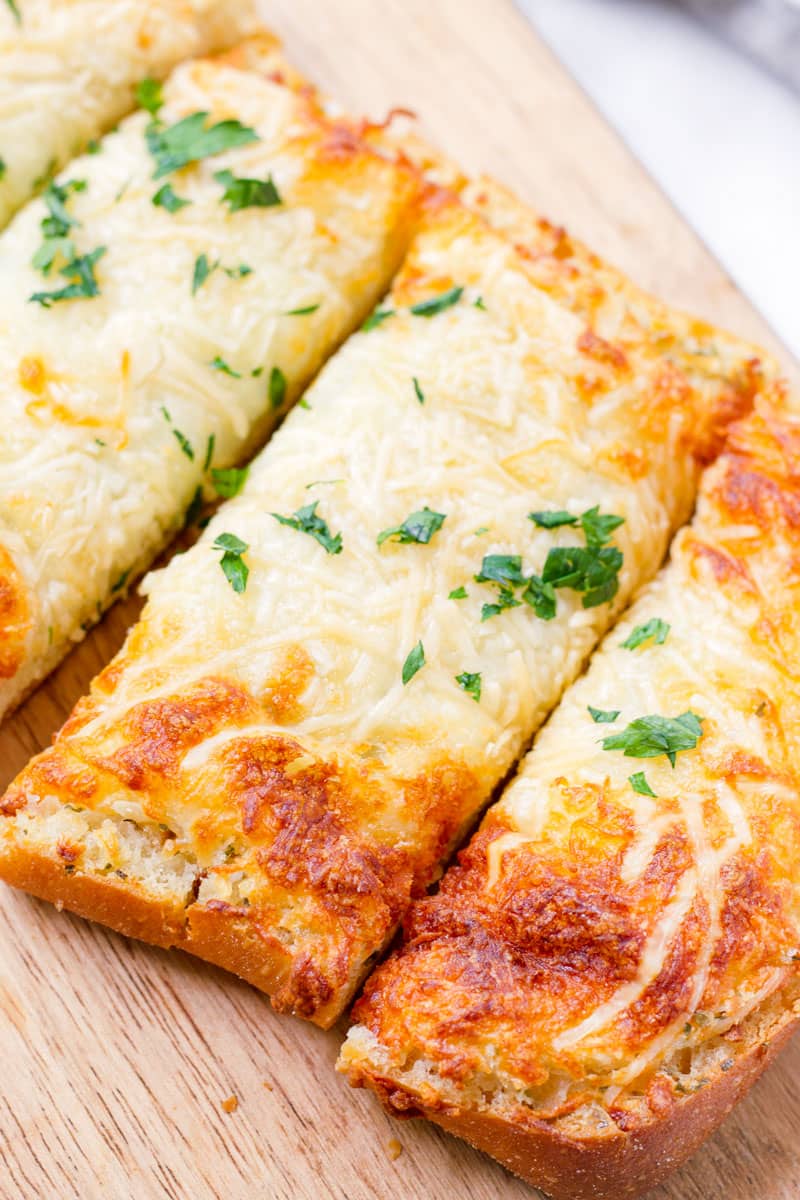 baked cheesy garlic bread cut into slices and served on a board