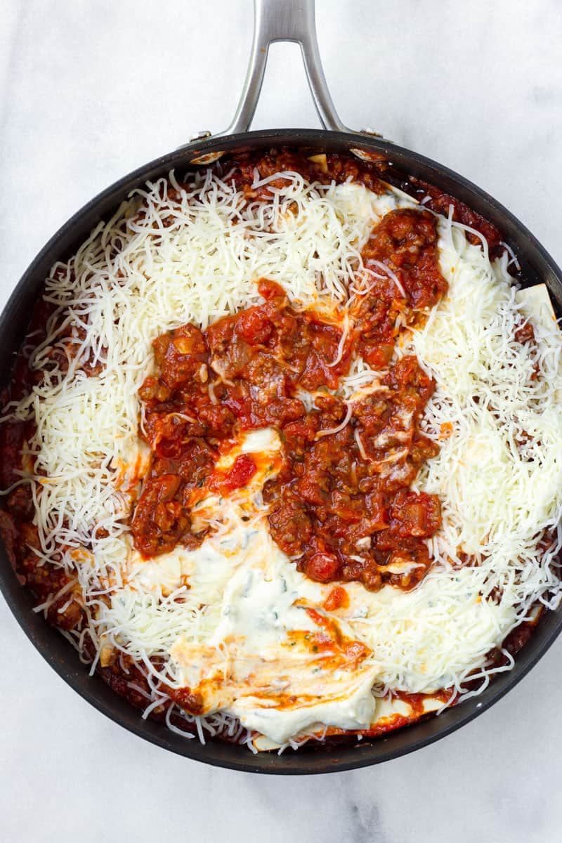 Deep skillet with layers of meat marinara sauce, mozzarella cheese, and ricotta