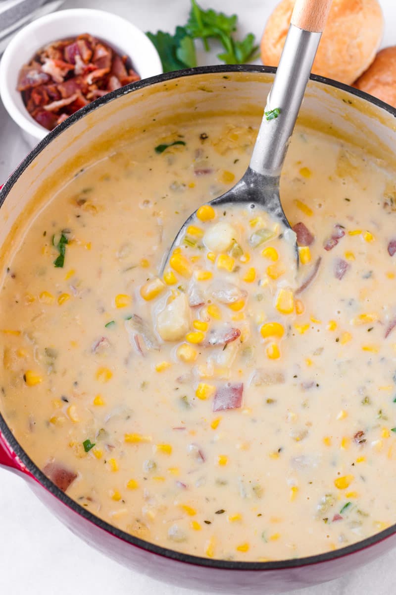 a ladle scooping out some creamy corn soup with potatoes