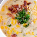 close up of a bowl of potato soup with bacon and parsley garnish