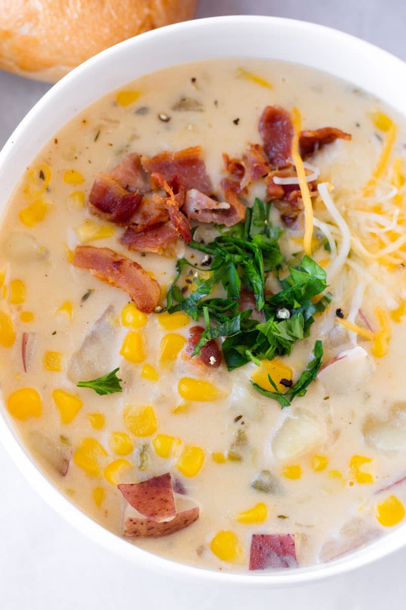 close up of a bowl of potato soup with bacon and parsley garnish