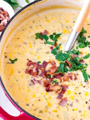 close of of a red Dutch oven filled with creamy potato and corn chowder with bacon