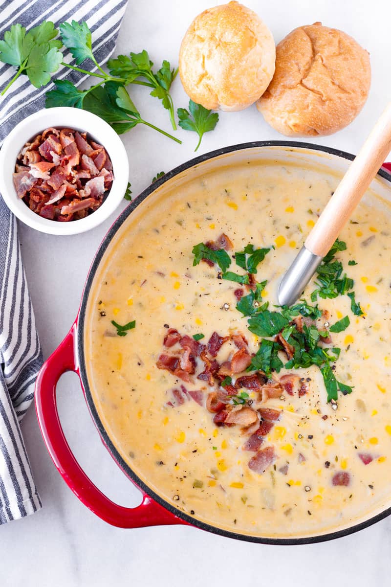 top view of potato corn chowder with bacon and parsley garnish, plus two bread rolls