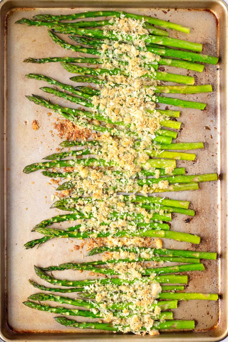sheet pan with prepared asparagus and breadcrumb cheese topping