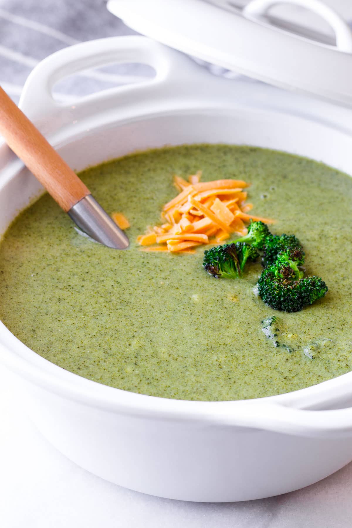 healthy kale and broccoli soup with garnish in a large serving pot and a serving ladle