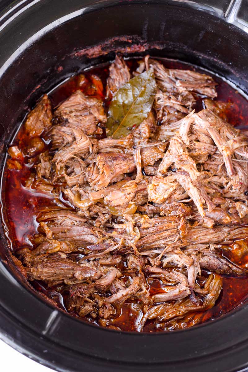 cooked shredded barbacoa beef in a slow cooker pot