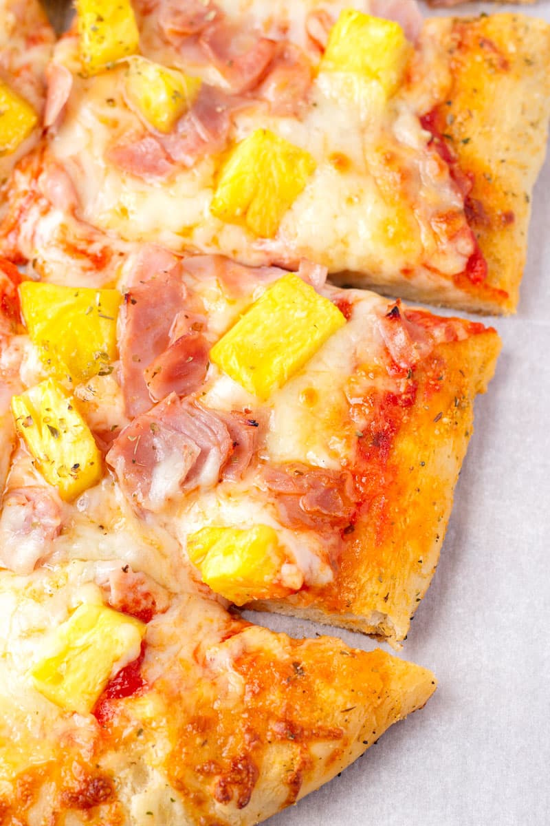 golden brown crust of a pizza made with pineapple and ham