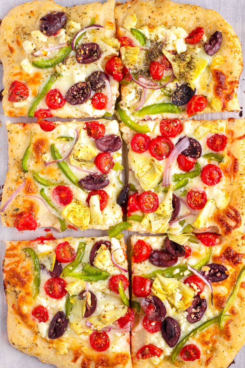 baked greek pizza in rectangular shape, sliced