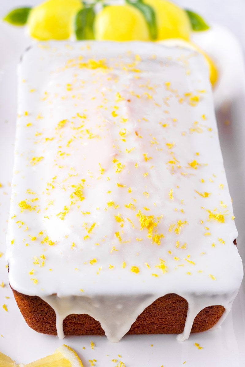 lemon icing drizzles on cake with lemon zest as garnish