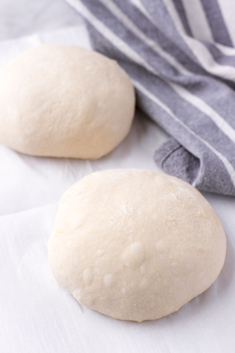 two pizza dough balls next to a towel