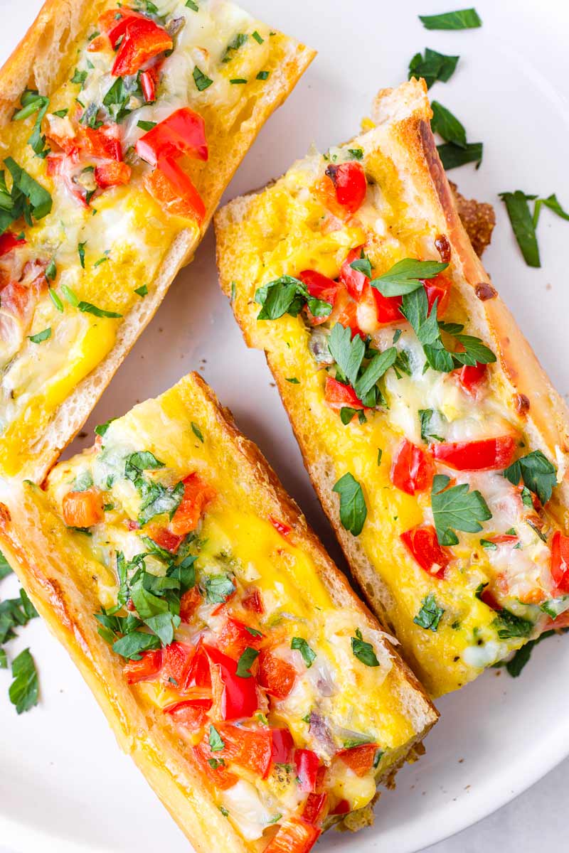 baked egg baguette split into three with herb garnish