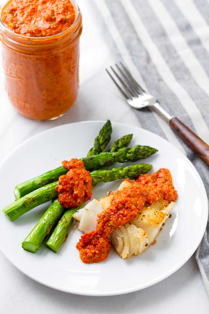 pan fried fish and asparagus on a plate with romesco