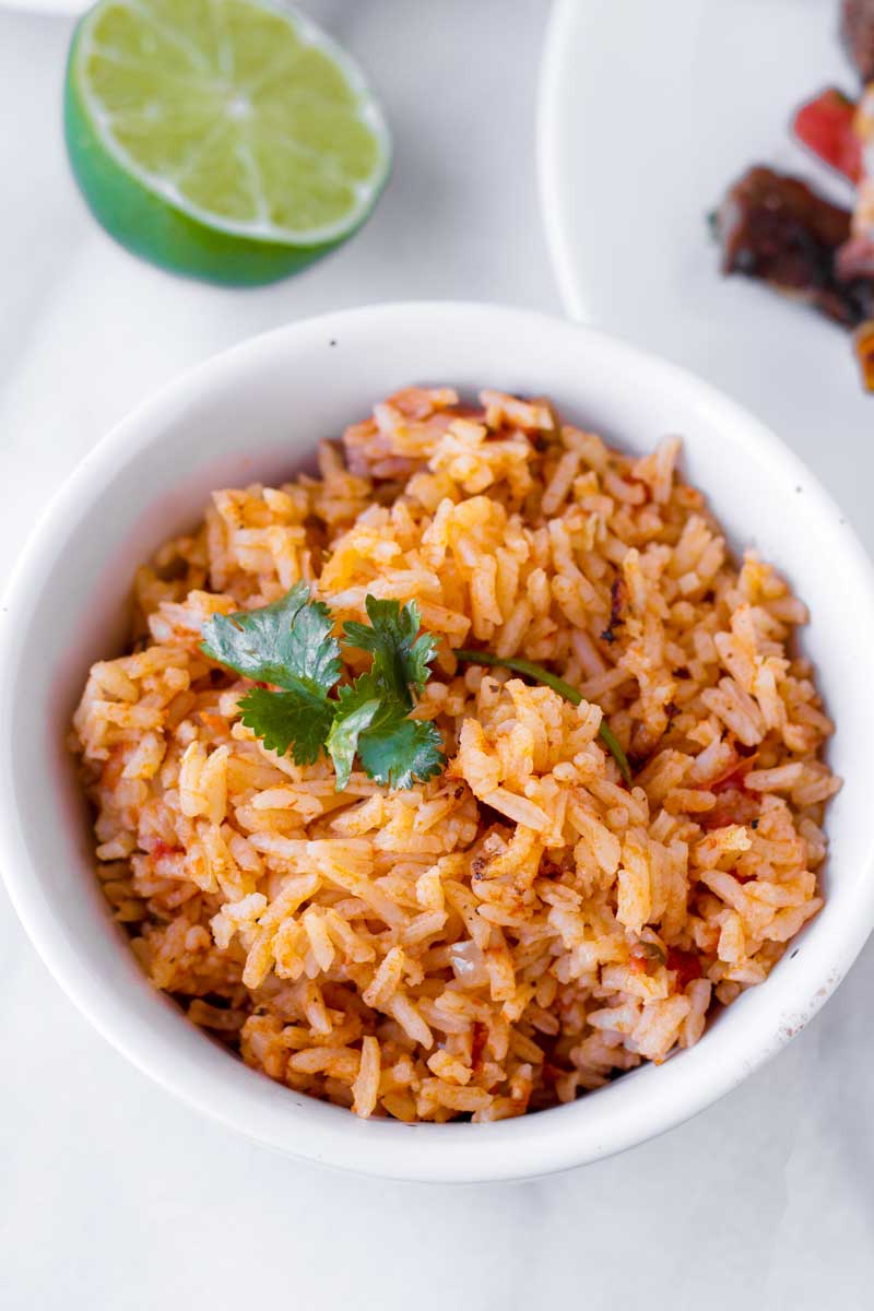 latin inspired rice served in a small bowl with half a lemon in the background