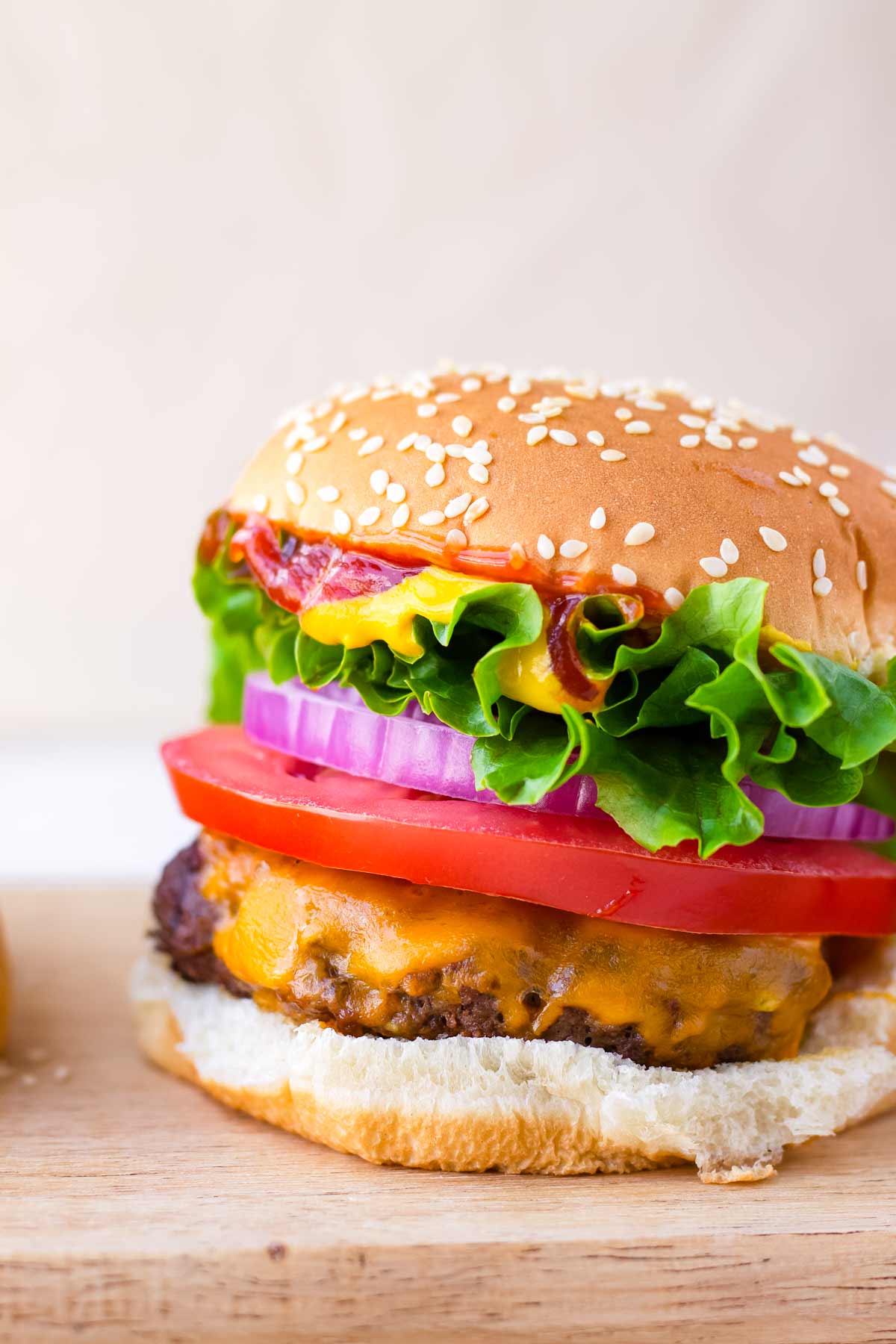 a classic American beef burger with lettuce, tomato, onion on a sesame bun