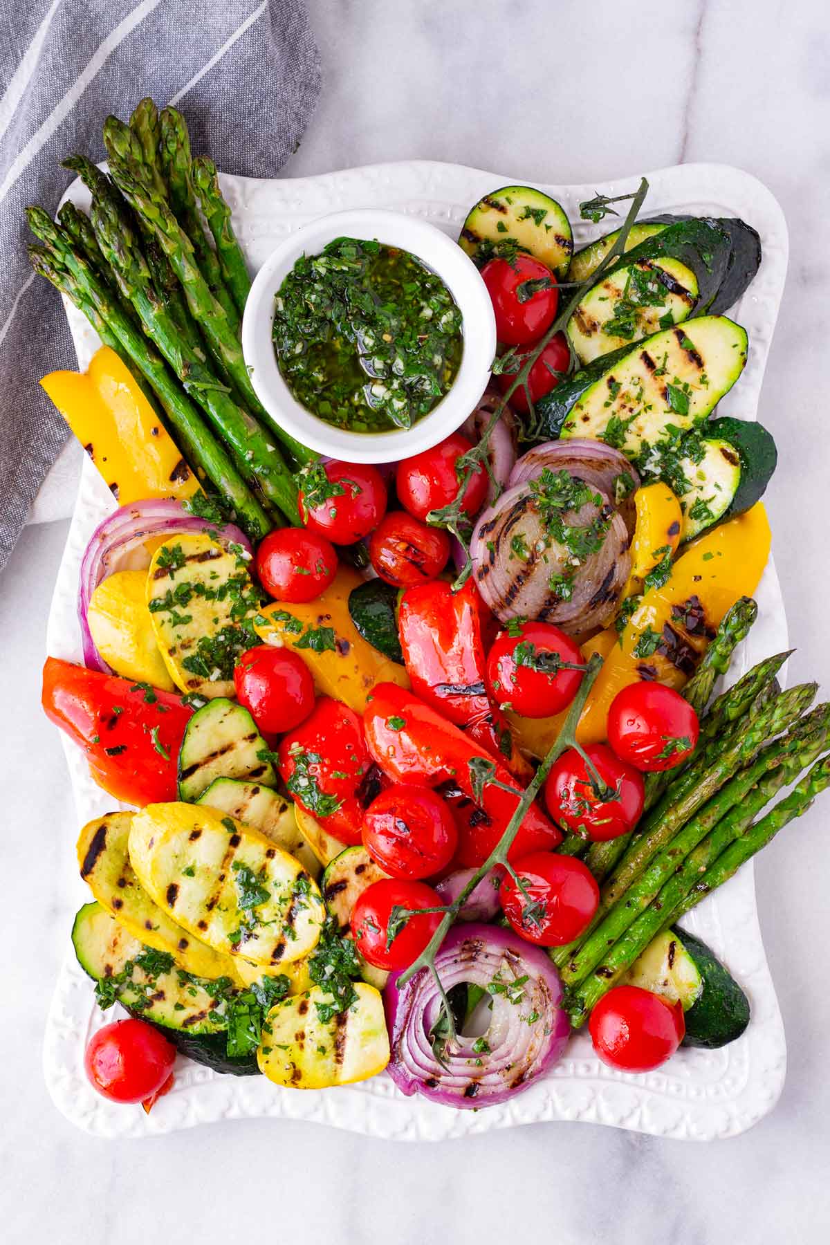 rectangular platter of arranged grilled vegetables and herb sauce