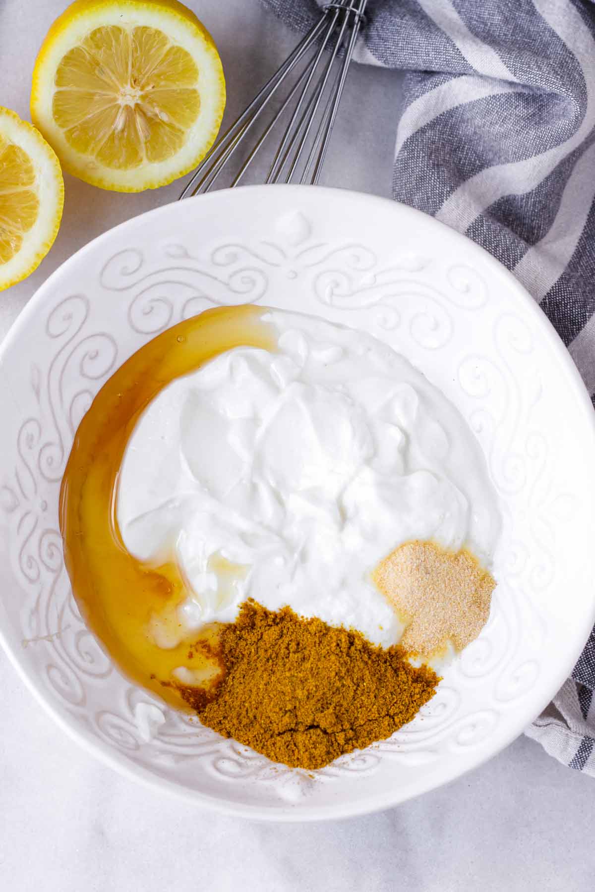 honey, curry powder, yogurt, garlic powder in a bowl and a sliced lemon