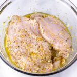 chicken breasts sitting in a lemon and garlic marinade