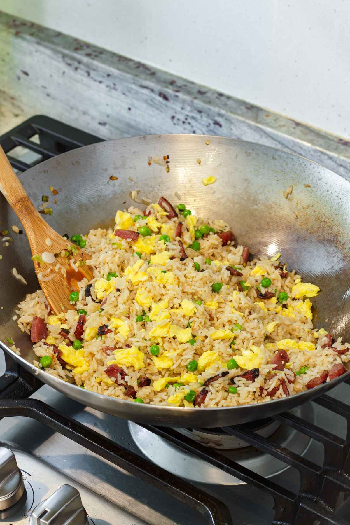 eggs added to a wok with chinese sausage fried rice