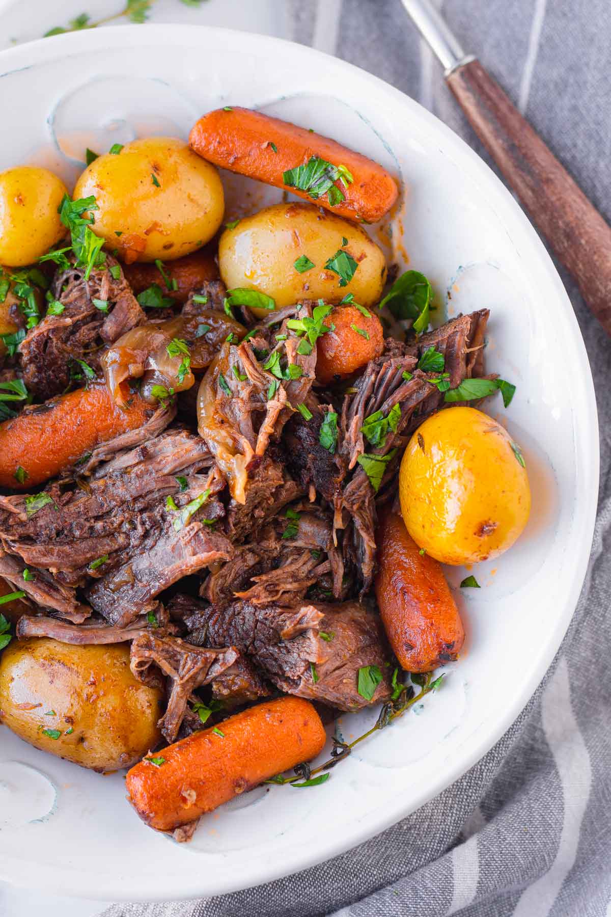 shredded beef with potatoes and baby carrots in a bowl