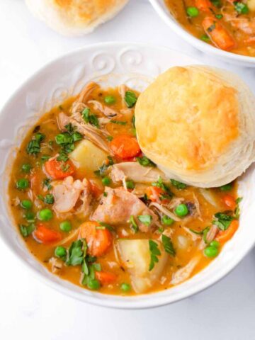 two bowls of crock pot chicken stew with biscuits