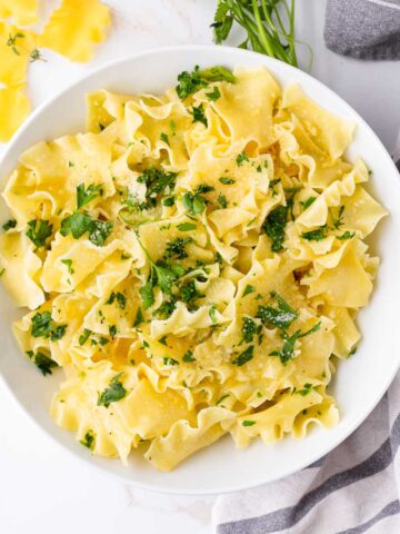buttered egg noodles with parmesan and parsley in bowl