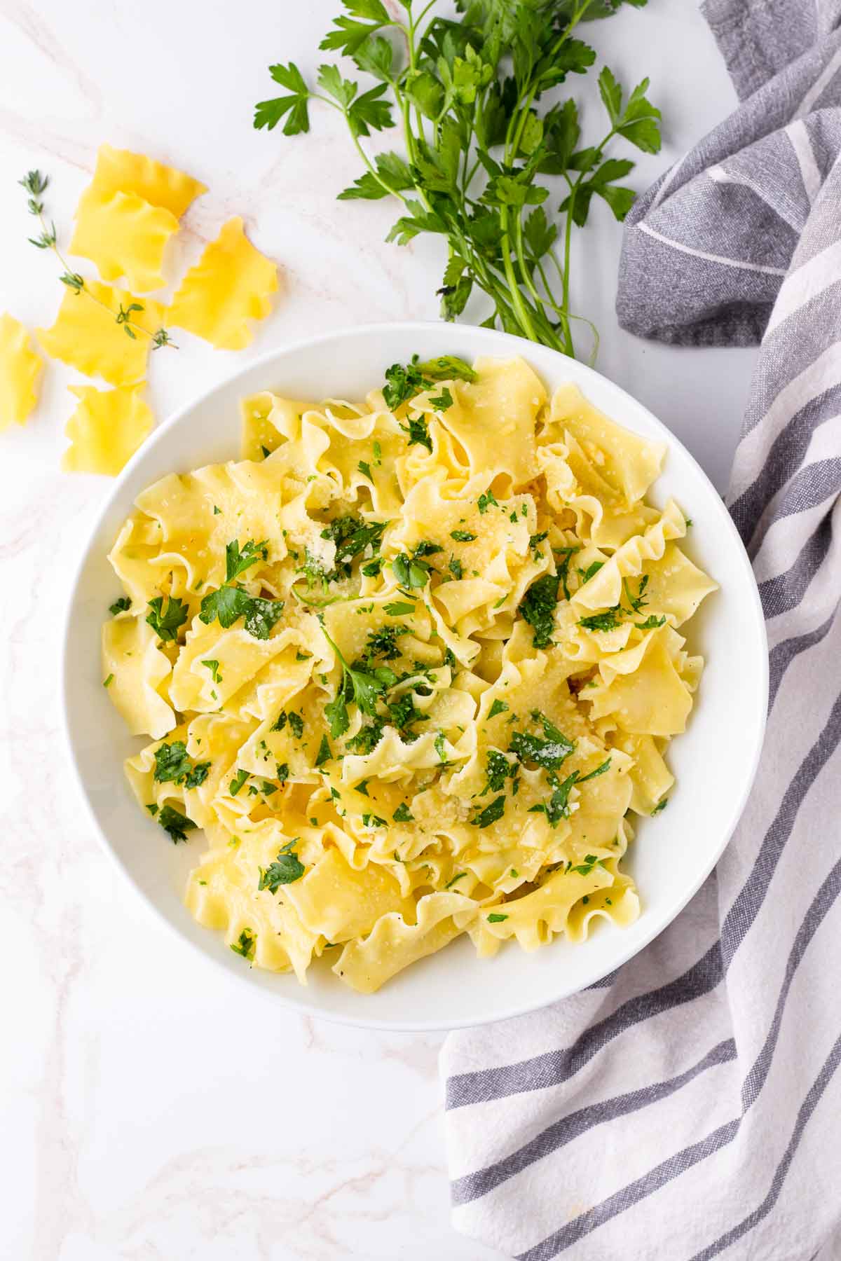 top view of buttered noodles with parsley and parsley in bowl