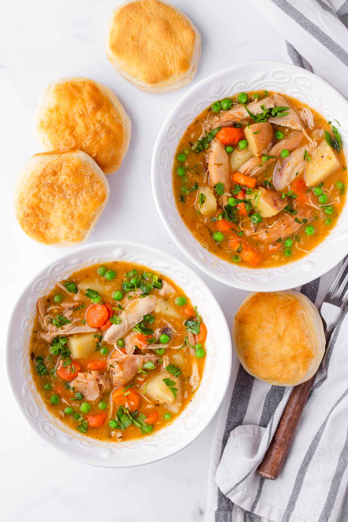 two bowls of slow cooked chicken stew with biscuit on the side
