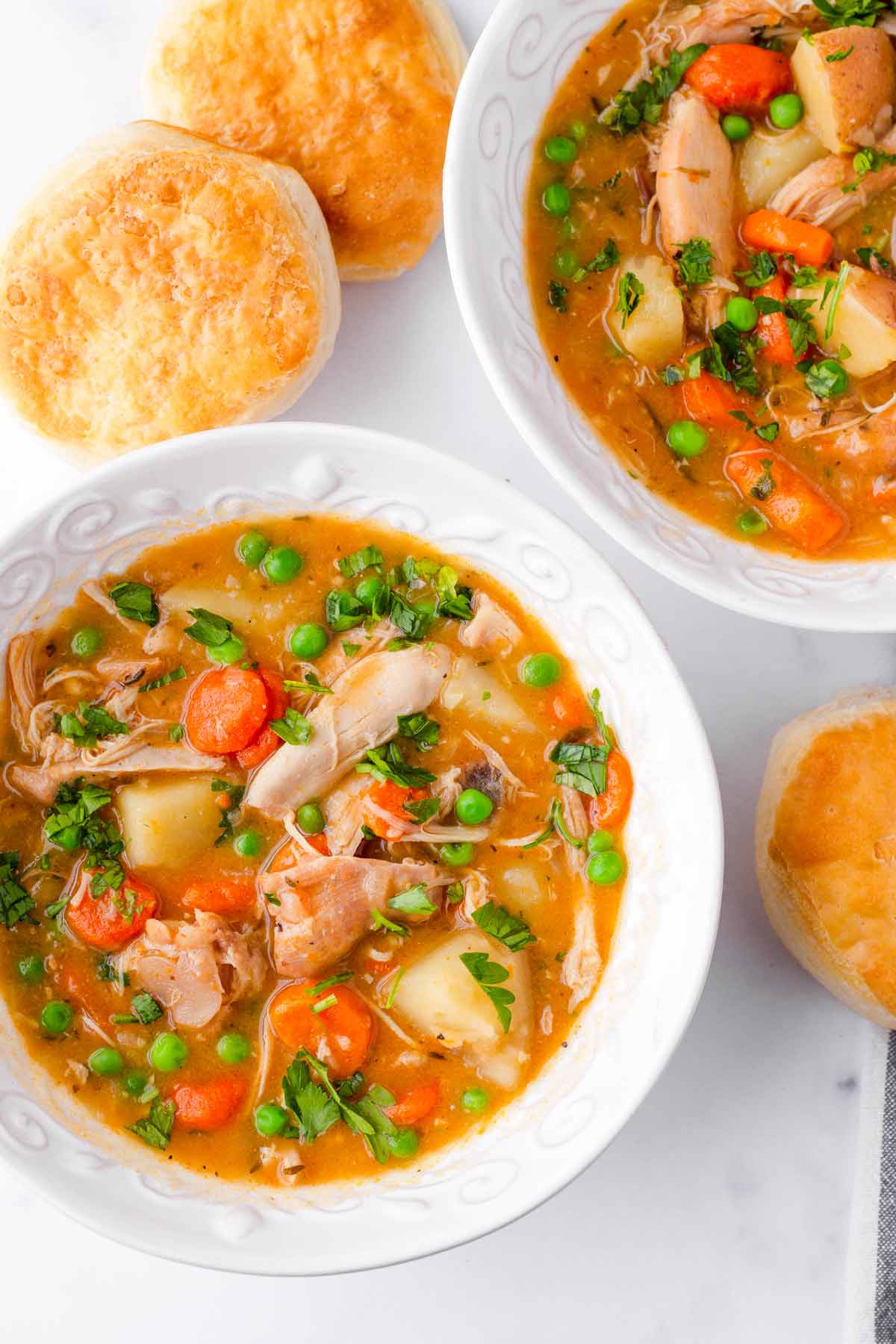 two bowls of tomato chicken stew with biscuits