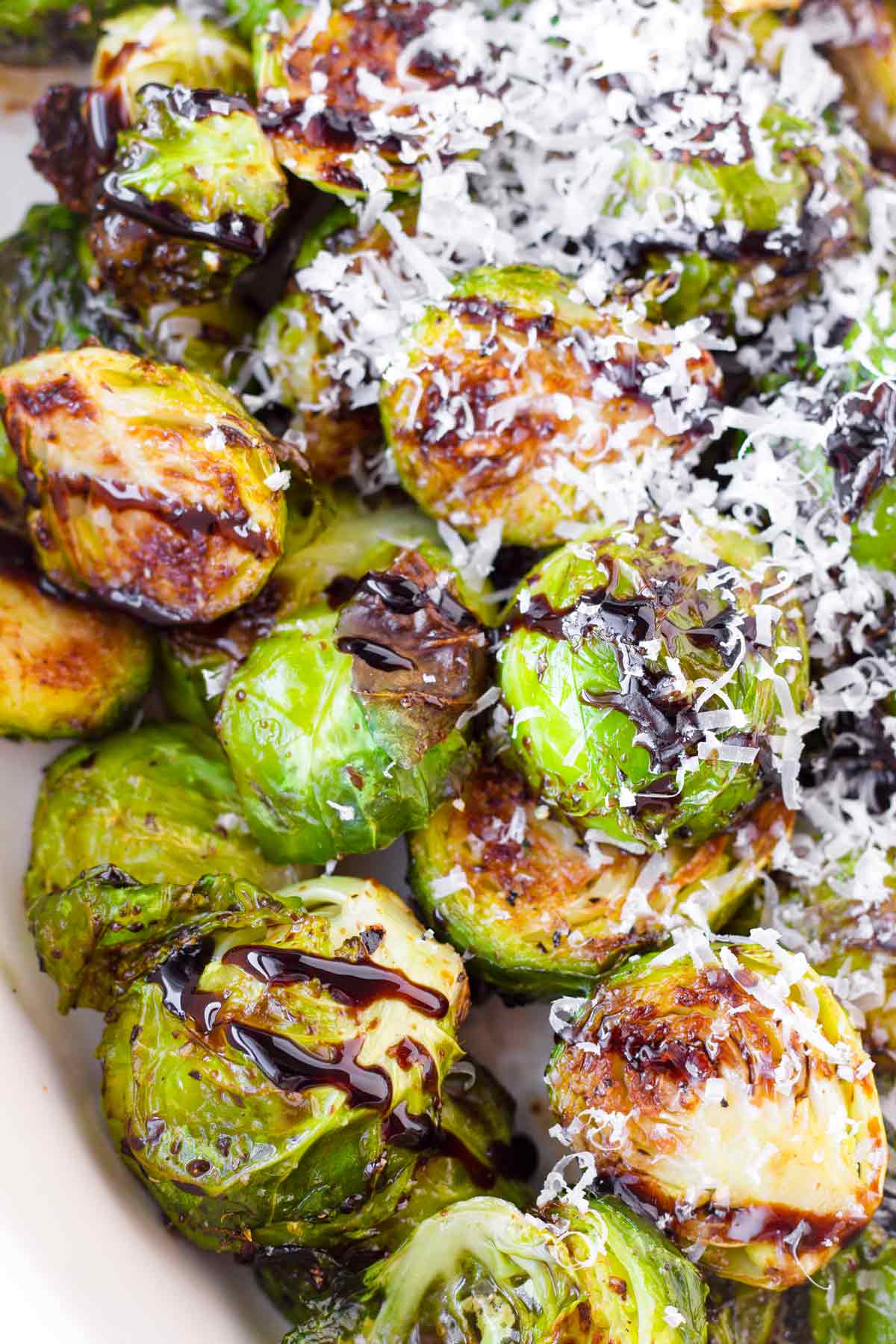 close up of roasted brussels sprouts with glaze with shaved parmesan cheese