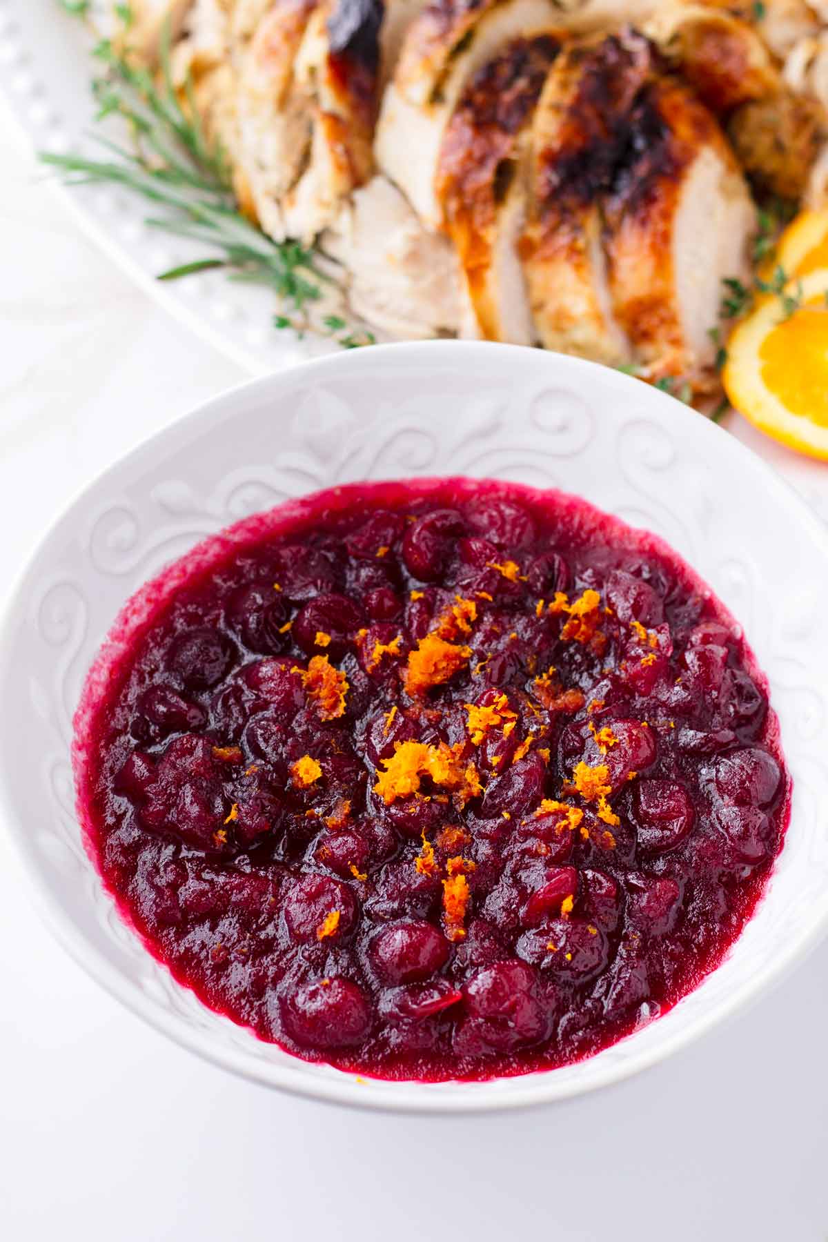a bowl of fresh cranberry sauce with turkey in the back