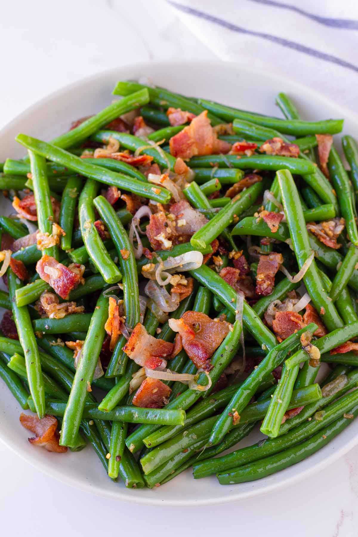 a plate with sauted green beans tossed with crispy bacon