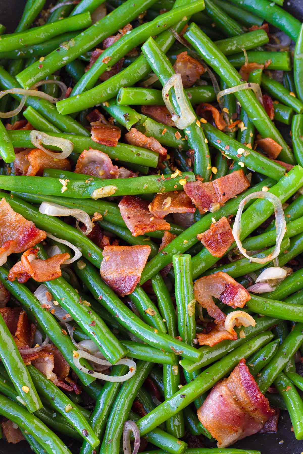 close up of sauted green beans tossed with bacon and shallots