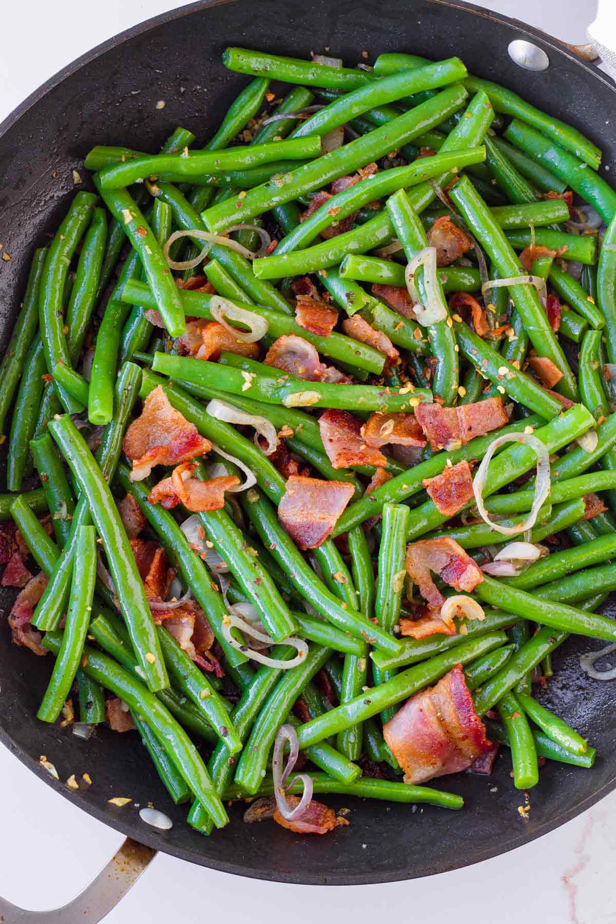 green benas with bacon, garlic, and shallots in skillet