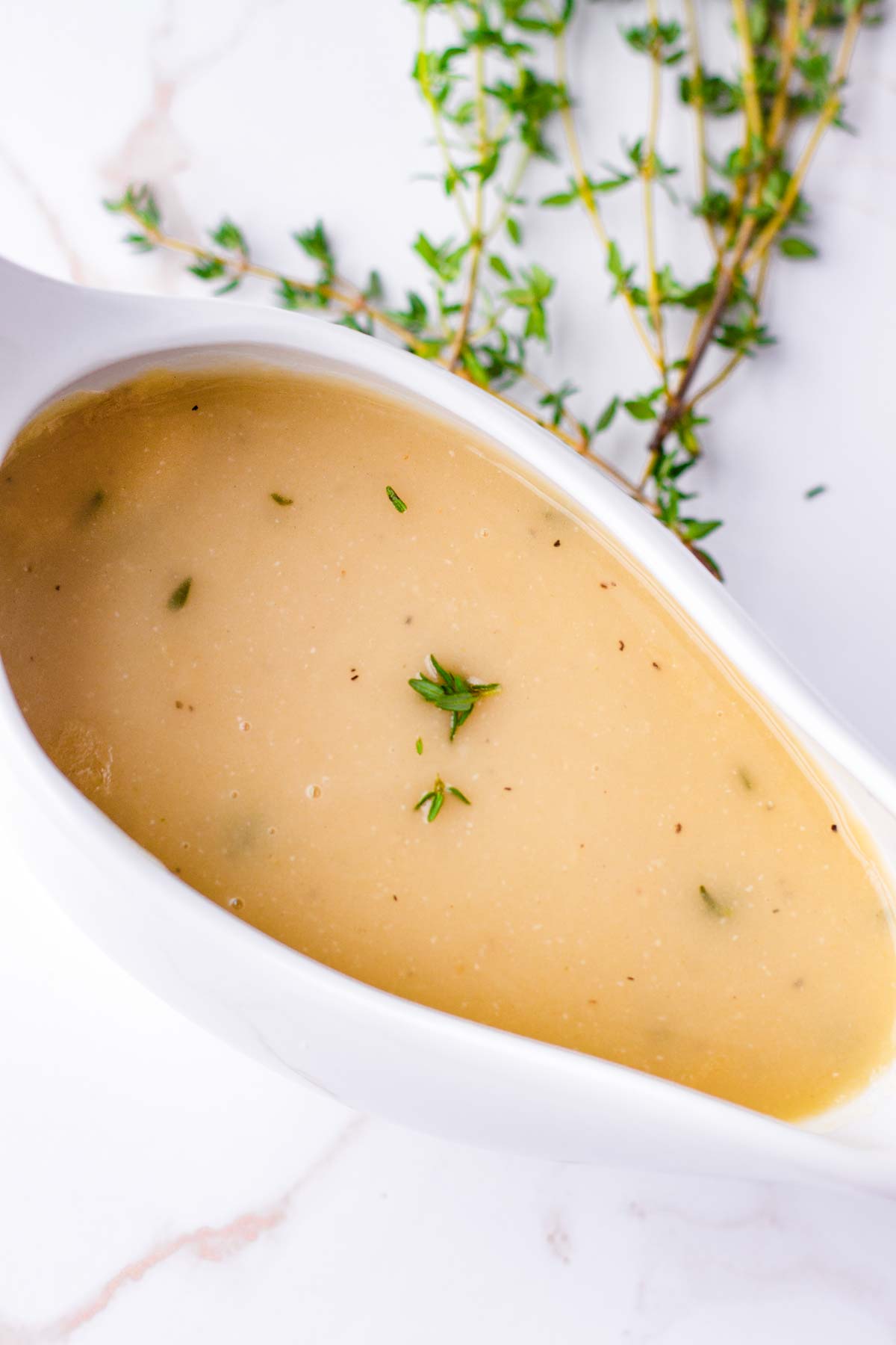 gravy in a serving bowl with thyme garnish