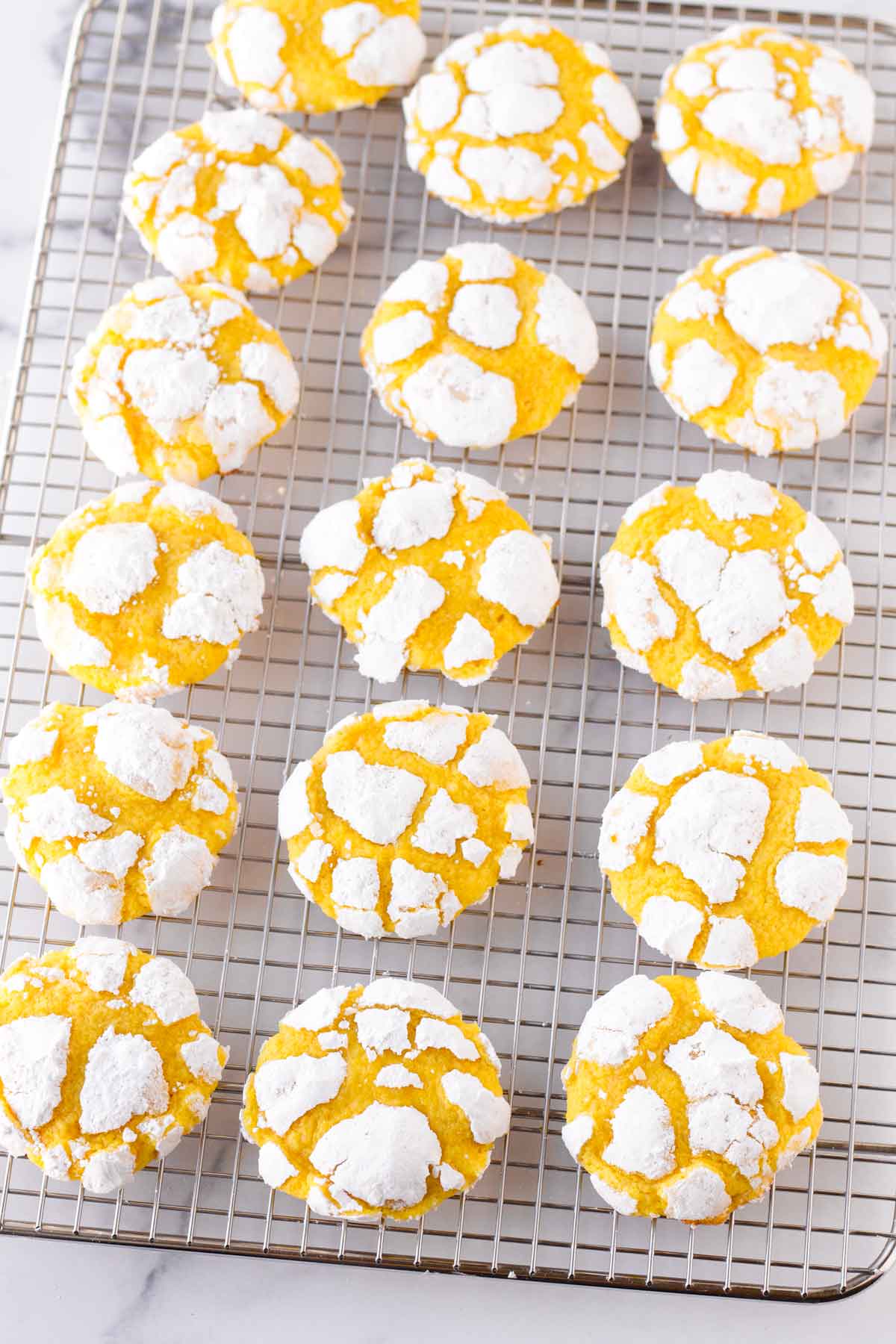 baked lemon crinkle cookies with powdered sugar on cooking rack