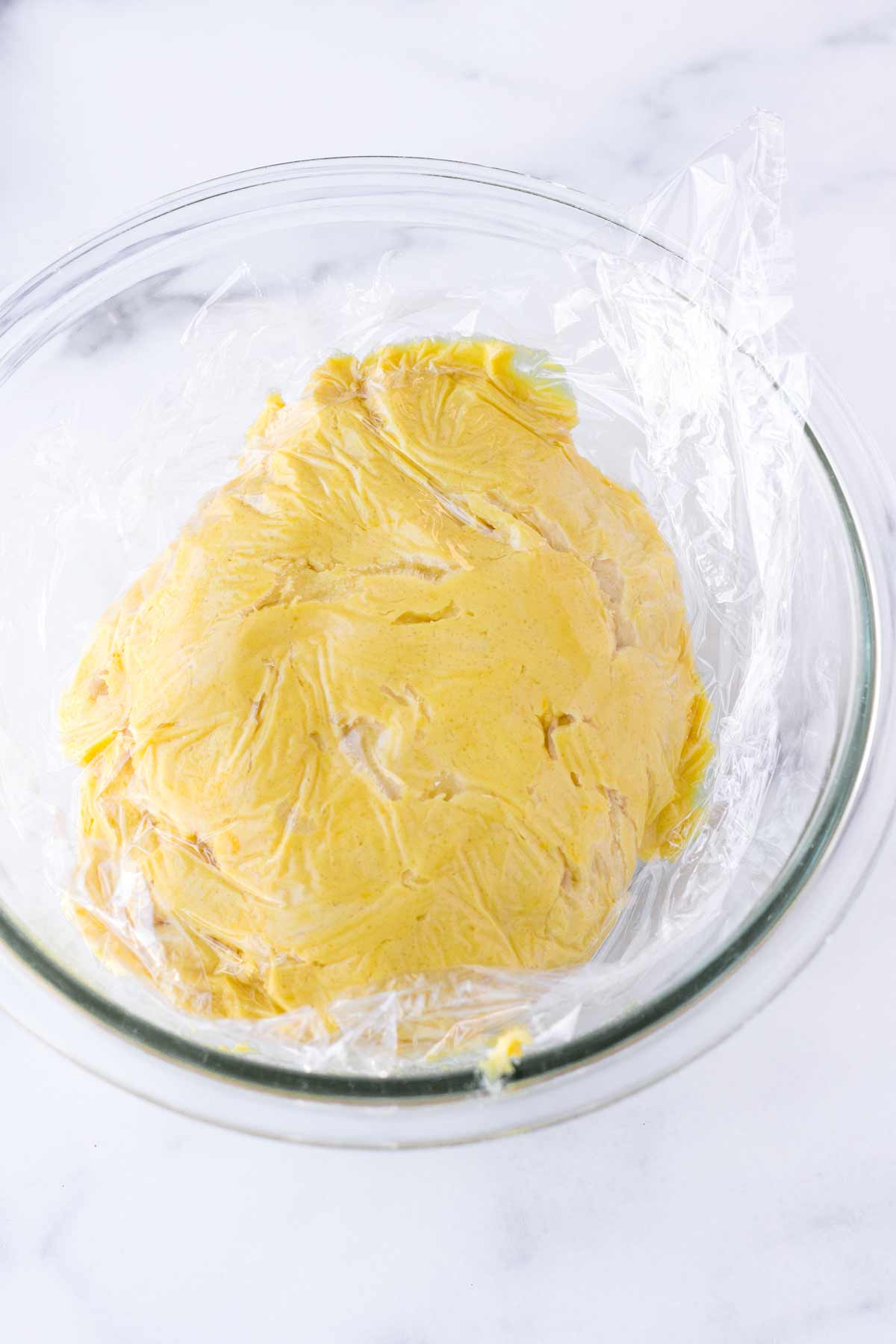 cookie dough covered with plastic wrap in bowl