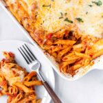 italian sausage pasta bake with melted cheese on a tray and plate