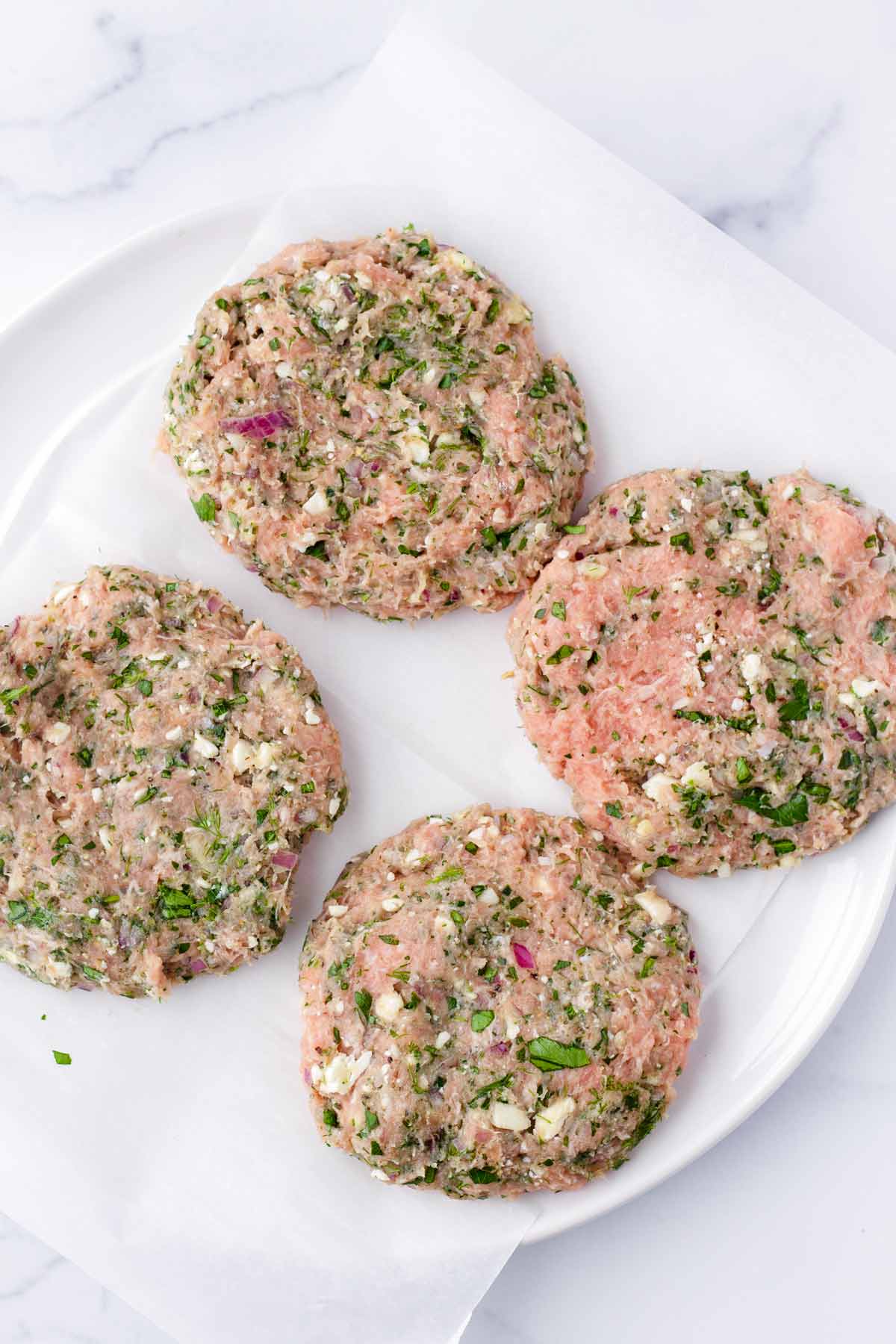 four uncooked turkey and feta burger patties on plate