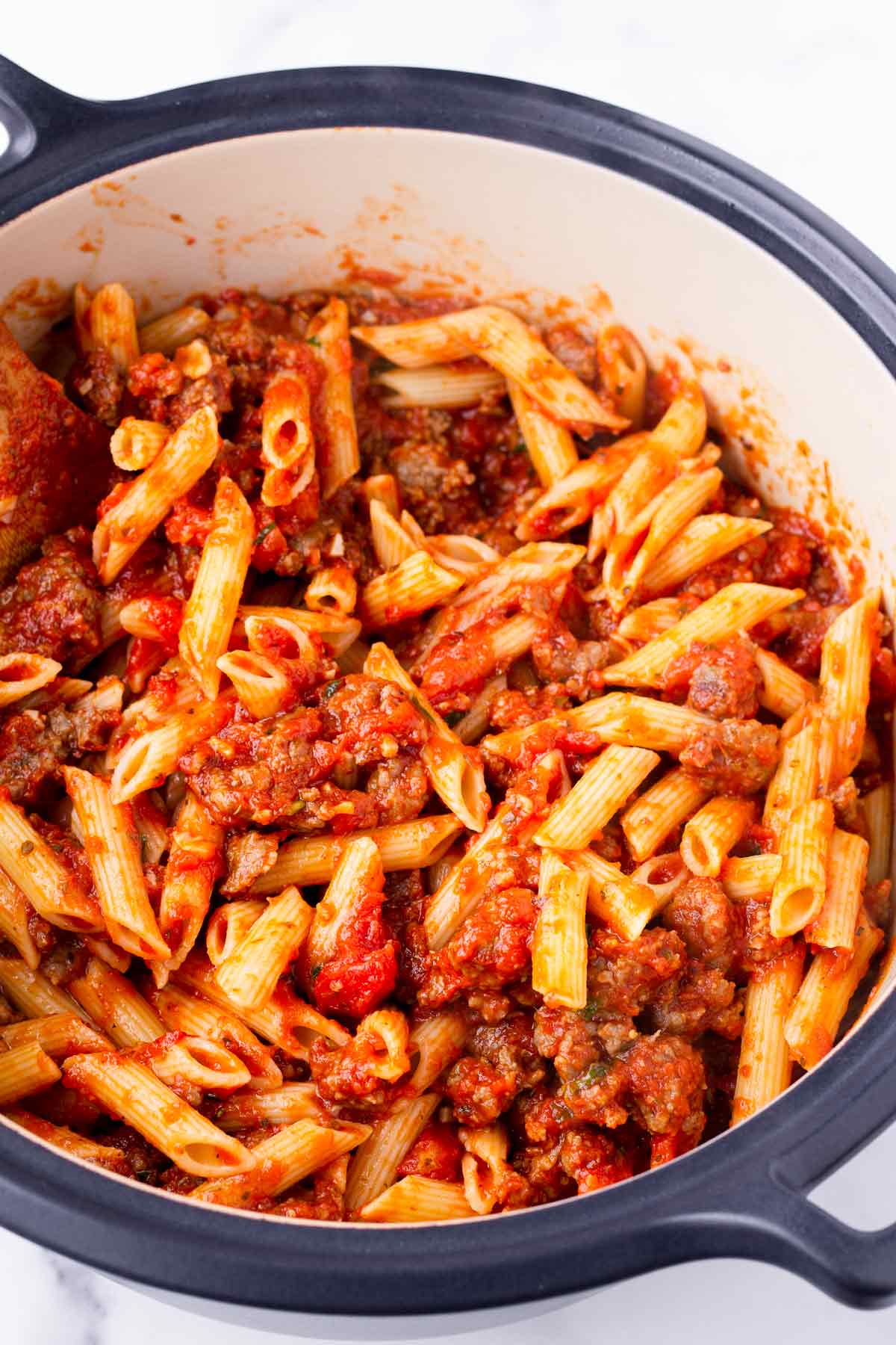 pasta tossed with sausage and marinara sauce in a pot