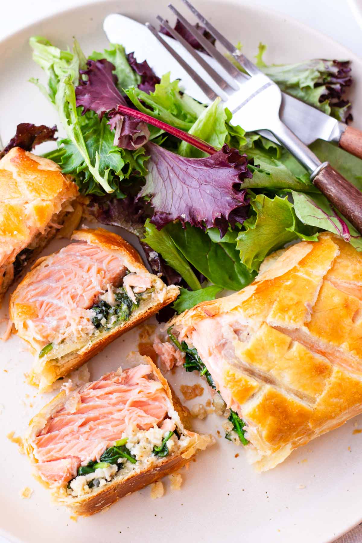salmon wrapped in puff pastry cut into slices and served with mixed greens
