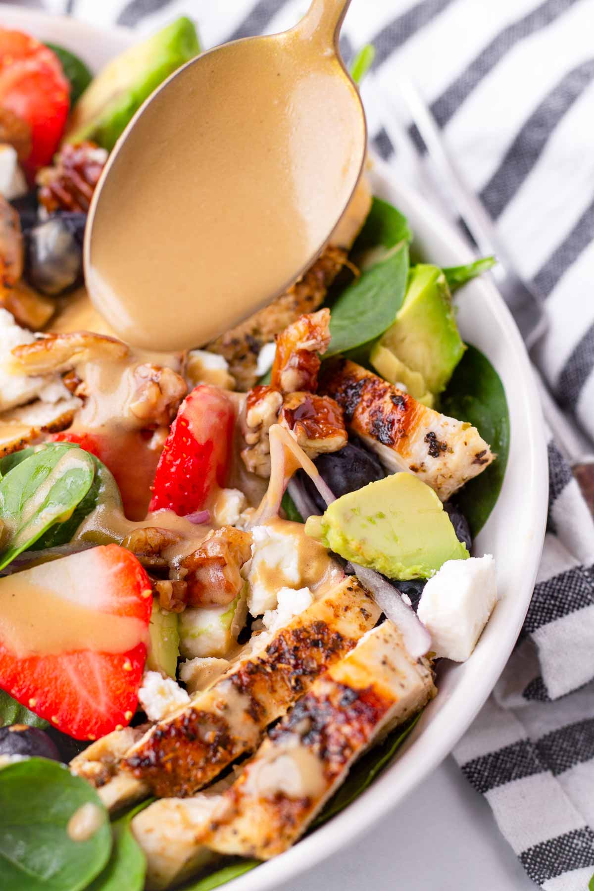 a spoon drizzling creamy balsamic dressing over salad