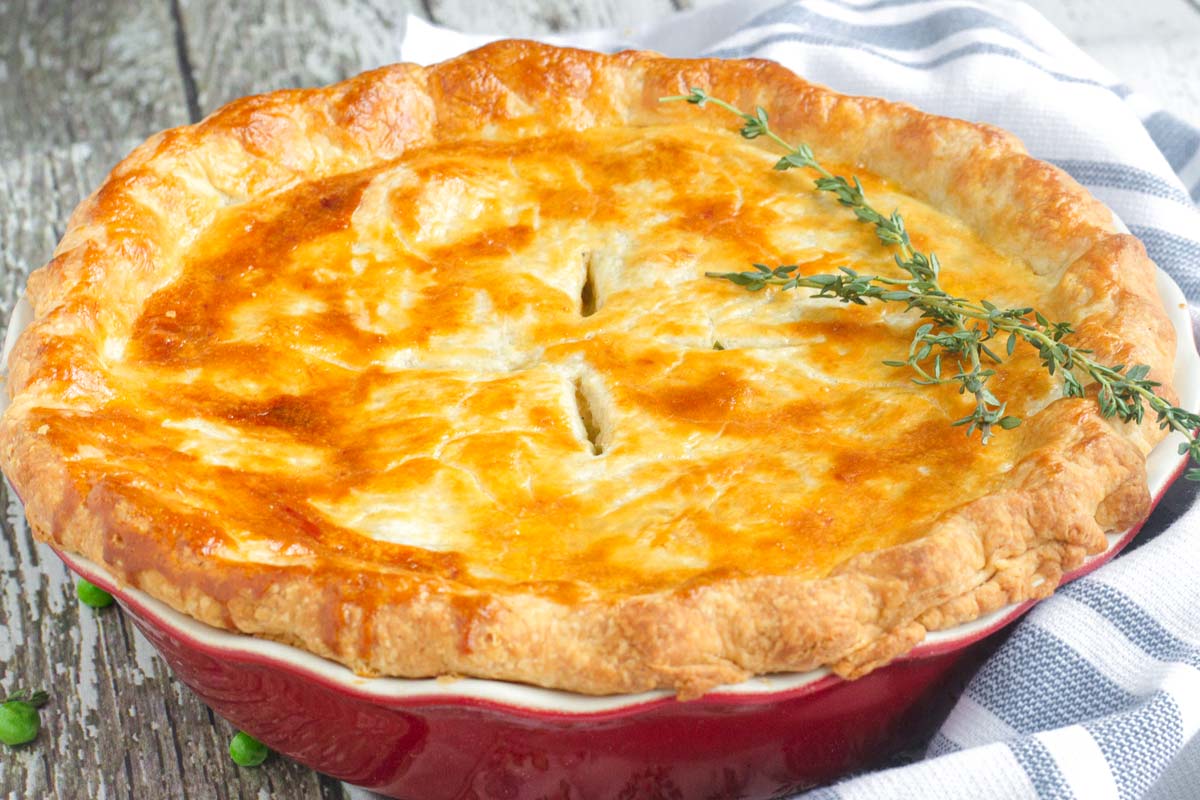 baked pie with golden brown top crust and thyme garnish