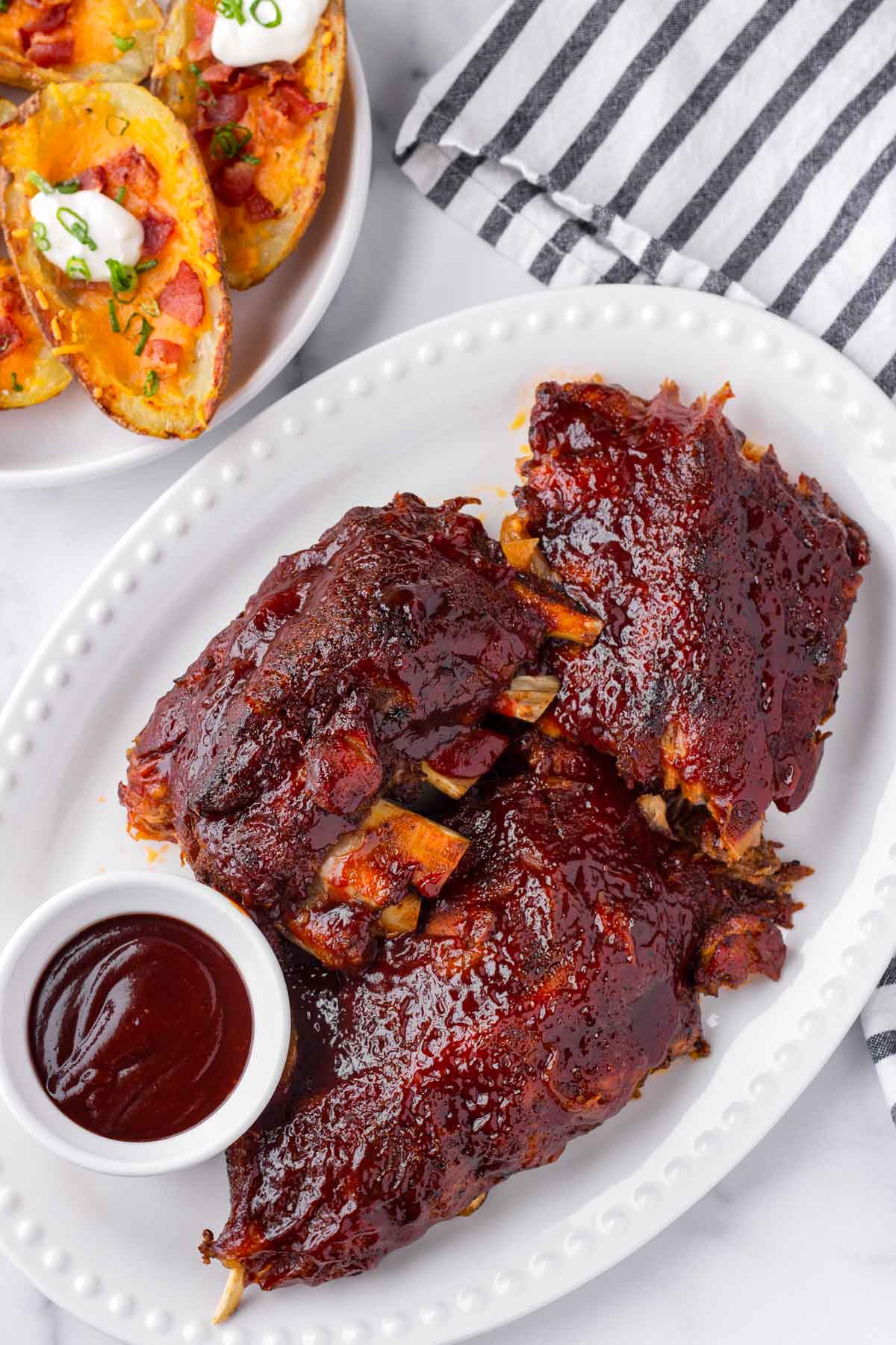 a plate of BBQ baby back ribs served with a side of potatoes