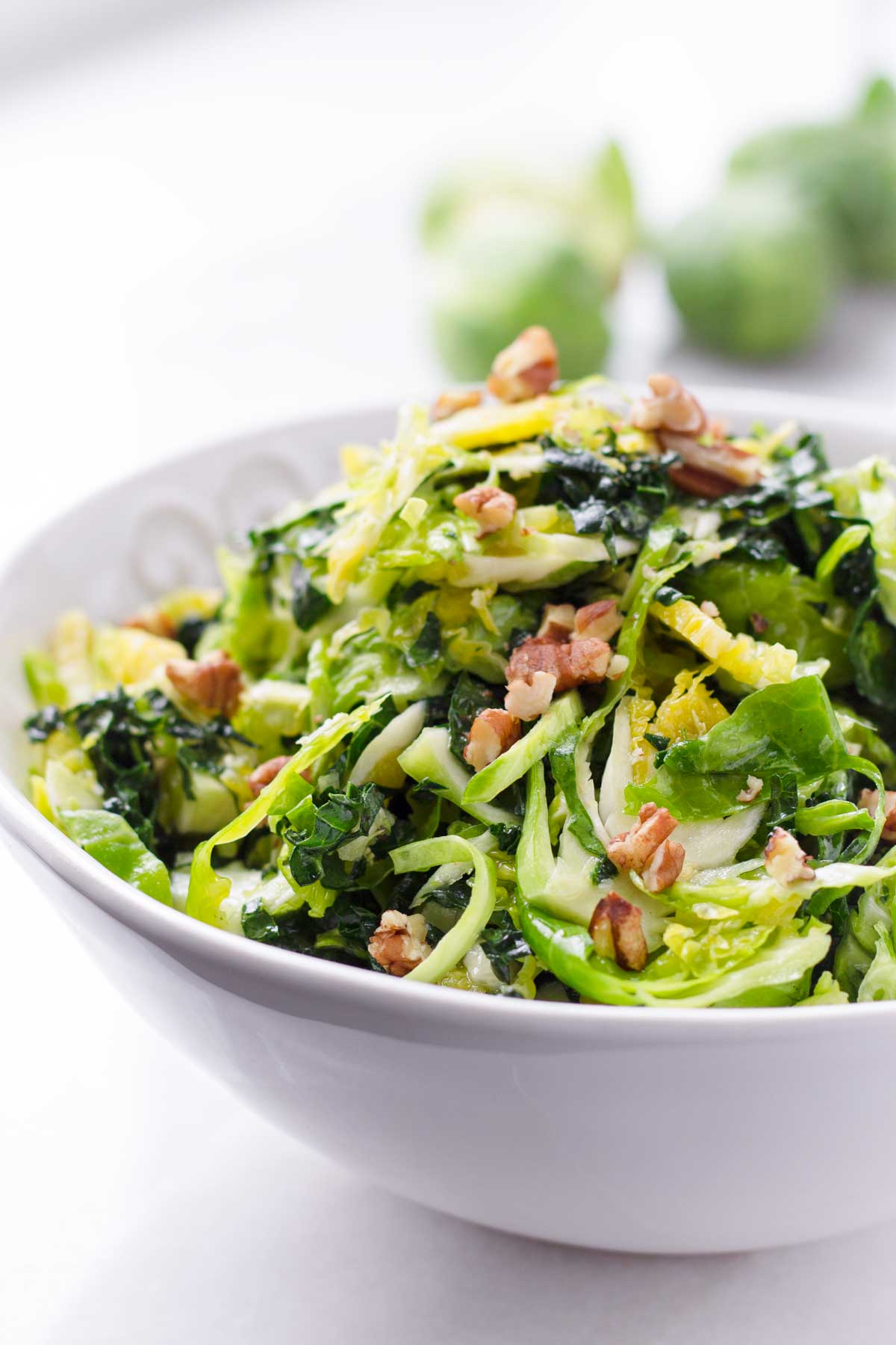 bowl of shaved brussels sprouts salad with chopped pecans