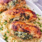 three pieces of spinach and cheese chicken breasts on top of couscous