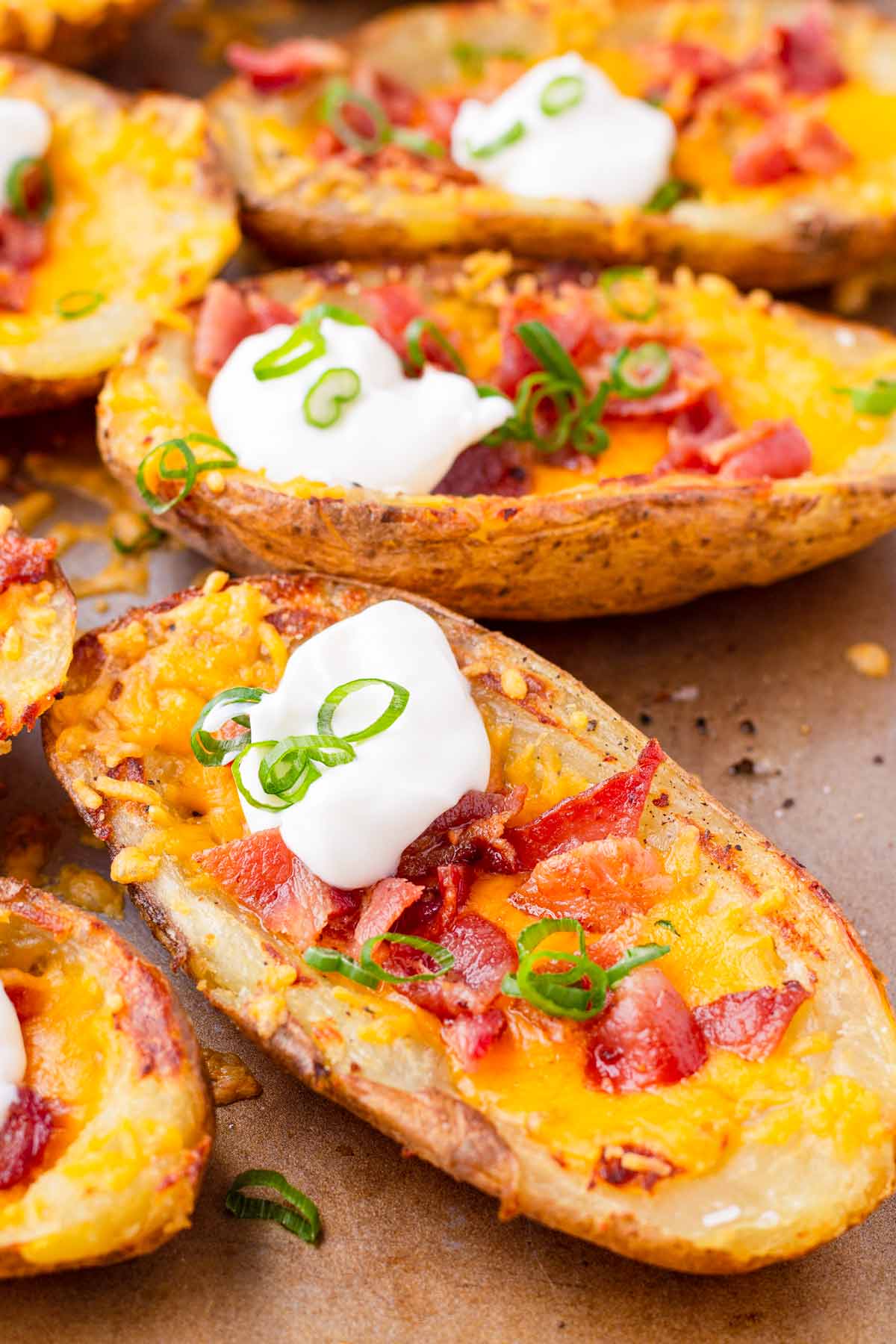 close up of one potato skin loaded with cheese, bacon, and toppings