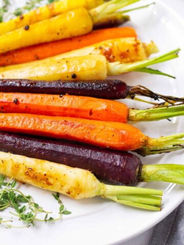 side view of roasted rainbow carrots with seasoning and glaze
