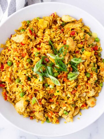 garnished yellow curry fried rice in round bowl