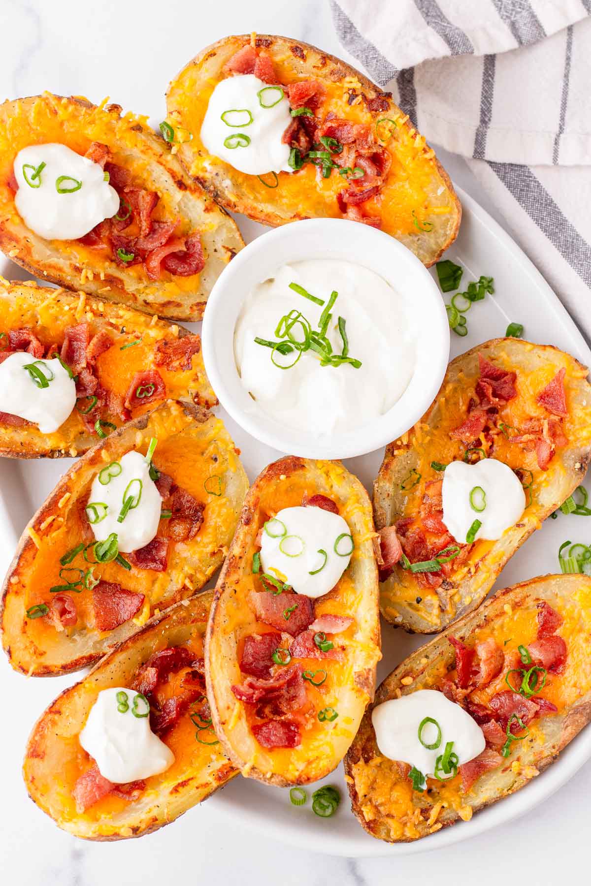 an oval serving platter with crispy russet potato skins with sour cream
